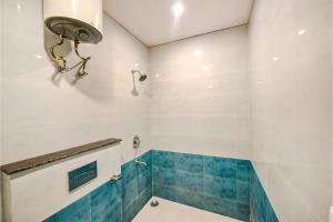 a bathroom with white walls and blue tiles at Hotel Alaknanda Paradise in Dehradun
