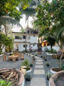 a garden with benches and trees in front of a building at Bayou Homestay and backwaters in Goa +39 photos