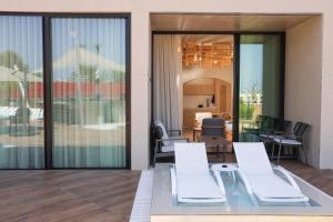 a living room with a glass table and white chairs at Inanna Resort in Batroûn
