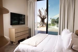 a bedroom with a white bed and a television at Inanna Resort in Batroûn +53 photos
