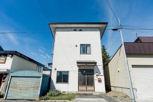 a white house with a black door at Cabin Build Take - 竹 in Biei