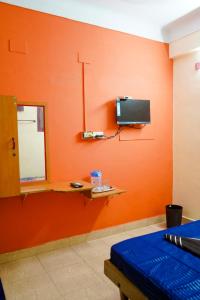 a room with an orange wall with a tv and a bed at Sri Uduppi Lakshmi Vilas Hotel in Madurai