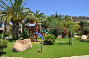 a playground in a yard with palm trees and a rock at Green Village Resort in Villasimius