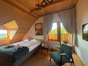 a bedroom with a bed and a chair and windows at Michałówka na Kubalowej Łące in Szczyrk