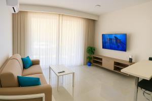 a living room with a couch and a tv on a wall at Penelope Apartments 15 in Xlendi