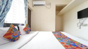 1 dormitorio con cama blanca y almohadas coloridas en Nakshatra residency, en Coimbatore