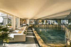 a swimming pool with couches and chairs in a building at Golserhof in Tirolo