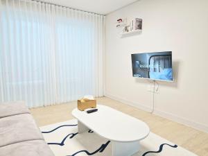 a white living room with a white couch and a tv at Stay Dasony in Gyeongju
