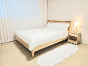 a bedroom with a bed with a white bedspread and a white rug at Stay Dasony in Gyeongju