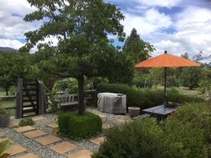 an orange umbrella and a picnic table and a table and a bench at hawea river retreat in Albert Town