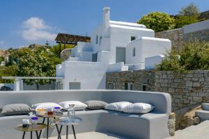 un banco con almohadas y mesas frente a un edificio en Venti Villa Naxos, en Naxos Chora