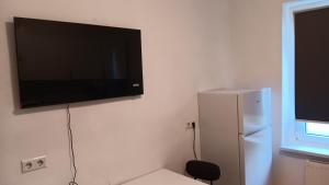a flat screen tv hanging on a wall next to a refrigerator at Crew Quartier ALL-INCLUSIVE Serviced Apartment in Krostitz in Krostitz