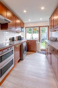 a large kitchen with wooden cabinets and stainless steel appliances at Pass the Keys 3-Bedroom Home in Chelmsford Sleeps 7 in Great Baddow