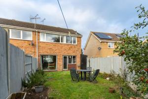 a backyard with a table and chairs and a house at Pass the Keys 3-Bedroom Home in Chelmsford Sleeps 7 in Great Baddow