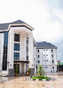 un edificio blanco con un árbol en el patio en Asato Hotel, en Asaba