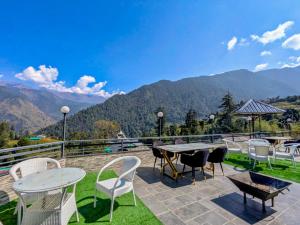 a patio with tables and chairs and mountains in the background at Heavenly Retreat, Shangarh in Shangarh