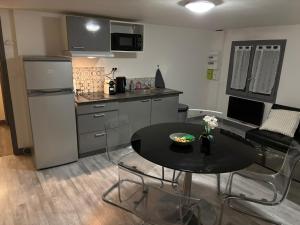 a small kitchen with a black table and chairs in a room at Le Nid du Sablard in Limoges
