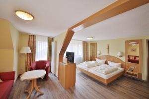 a hotel room with a bed and a tv and a couch at Hotel Restaurant Freihof in Oberharmersbach