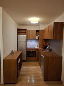 een keuken met houten kasten en een roestvrijstalen koelkast bij Très bel appartement dans le centre d'Isola 2000 avec balcon exposé sud ouest in Isola 2000