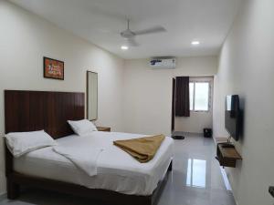 a bedroom with a bed and a flat screen tv at Hotel O SSR residency in Chennai