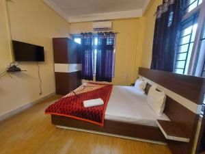 a bedroom with a large bed and a flat screen tv at Hotel O SUNLEAF GUEST HOUSE in Dispur