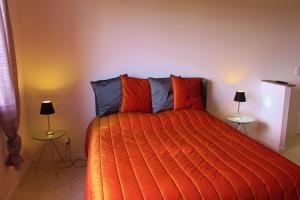 a bedroom with a bed with an orange blanket and two lamps at Le Haras du Favry in Palinges