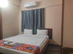 a bedroom with a bed with a blue curtain and a window at HOTEL O THE HOTEL TRIYA in Warangal