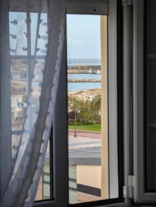 a window with a view of a beach and the ocean at Olladas de Laxe Apartamento con vistas in Laxe