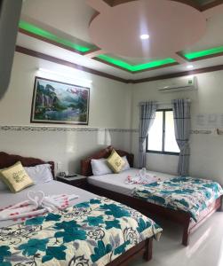 twee bedden in een kamer met groene lichten aan de plafonds bij Nhà Nghỉ Việt Thắng Dinh Thầy Thím in La Gi +29 foto's