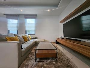un salon avec un canapé et une grande télévision à écran plat dans l'établissement Nicky Villa Luxury Private Haven in BangTao Laguna, à Laguna Phuket