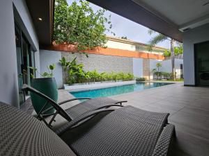 un patio avec des chaises et une piscine dans l'établissement Nicky Villa Luxury Private Haven in BangTao Laguna, à Laguna Phuket