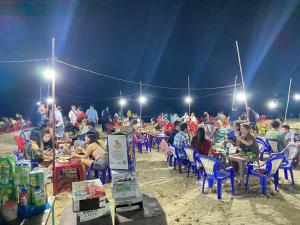 een groep mensen aan tafel op het strand bij Nhà Nghỉ Việt Thắng Dinh Thầy Thím in La Gi