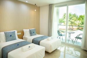 a hotel room with two beds and a balcony at Paradise Found in Dhigurah