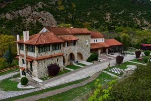 a large stone house with a road in front of a mountain at Muntenia Inn Apartments and Suites in Kalavrita