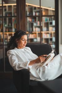 a woman sitting in a chair reading a book at Golserhof in Tirolo
