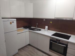 a kitchen with white cabinets and a sink and a refrigerator at Apartmani Sumatra in Srebrenica