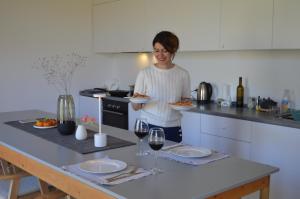a woman standing in a kitchen holding a plate of food at Nature Cabin in Dzhiviskli