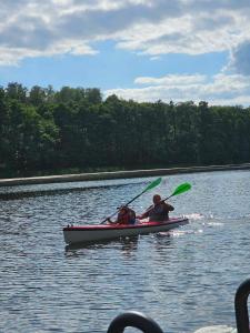 a man and a child in a canoe on a lake at Dom na Mazurach Zatoka Leśna in Wieniec
