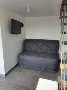 a couch in a room with a tv on the wall at DUPLEX BASSIN D'ARCACHON in Gujan-Mestras