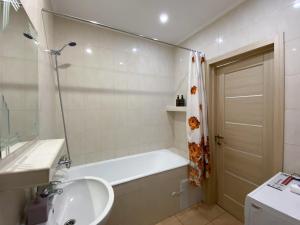 een badkamer met een bad, een wastafel en een douche bij Комфортна 1к квартира в ЖК Лісовий Квартал in Brovary