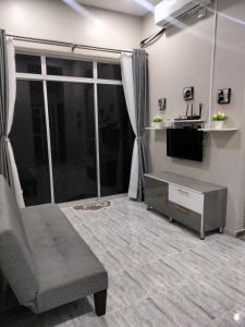 a living room with a couch and a tv and a window at Teratak Nu'aiman With Pool in Bedung