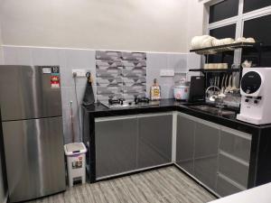 a kitchen with a stainless steel refrigerator and a counter at Teratak Nu'aiman With Pool in Bedung