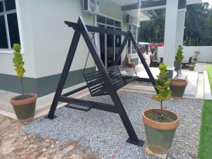a swing in front of a house with potted plants at Teratak Nu'aiman With Pool in Bedung