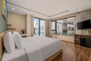 - une chambre avec un grand lit blanc et une télévision à écran plat dans l'établissement Happy House Hotel & Apartment, à Đà Nẵng