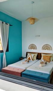 Dos camas en una habitación con paredes azules. en Villa CasaCocoa, en Hell-Ville