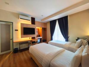 um quarto de hotel com duas camas e uma televisão em Raia Beach Resort Port Dickson em Port Dickson