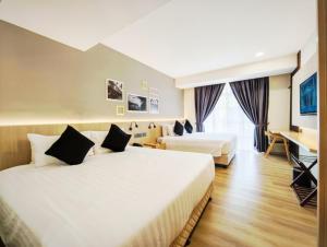 um quarto de hotel com duas camas e uma escrivaninha em Raia Beach Resort Port Dickson em Port Dickson