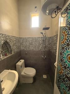 a bathroom with a toilet and a sink at Tilal Al-Qattara in Mashūq
