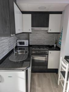 a small kitchen with white cabinets and a sink at Olladas de Laxe Apartamento con vistas in Laxe +10 photos