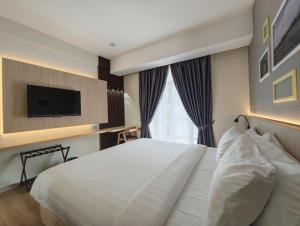 um quarto com uma grande cama branca e uma televisão em Raia Beach Resort Port Dickson em Port Dickson